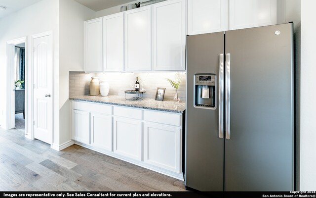 kitchen with light wood-type flooring, white cabinets, light stone countertops, and stainless steel refrigerator with ice dispenser