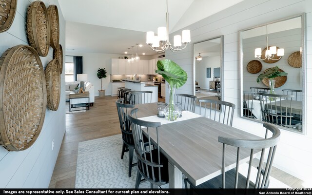 dining area featuring vaulted ceiling, ceiling fan with notable chandelier, and light hardwood / wood-style floors