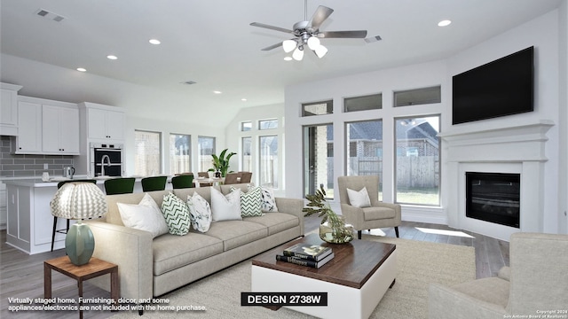 living room with lofted ceiling, ceiling fan, a wealth of natural light, and light hardwood / wood-style flooring