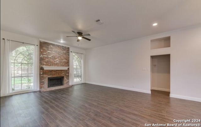 unfurnished living room featuring dark wood-type flooring, ceiling fan, and a brick fireplace