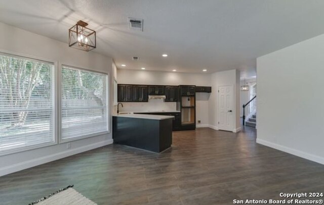 kitchen with kitchen peninsula, dark hardwood / wood-style floors, sink, and a notable chandelier