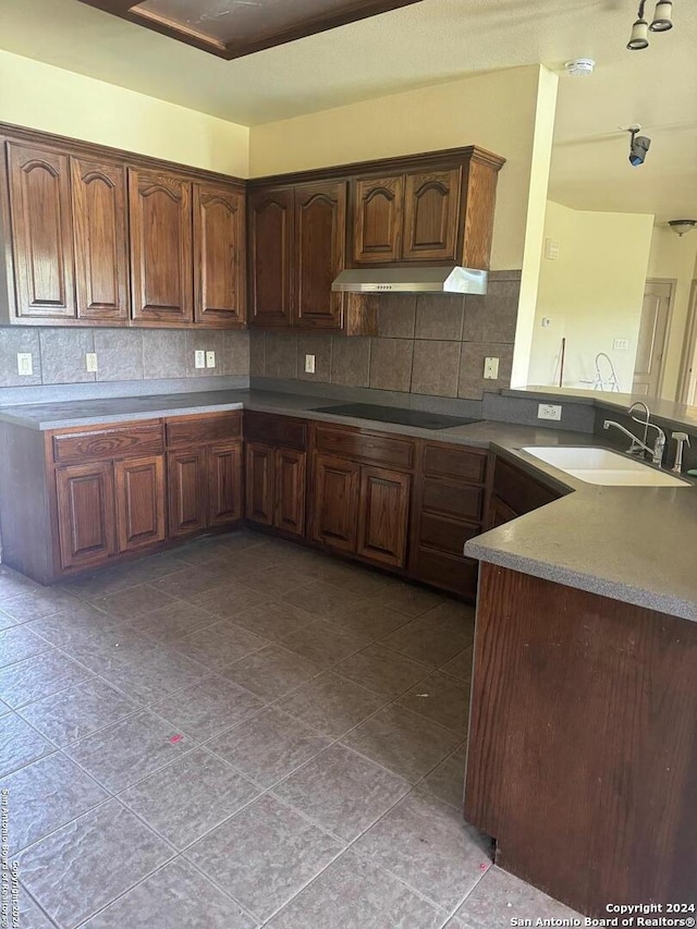 kitchen with light tile patterned flooring, sink, decorative backsplash, black electric stovetop, and kitchen peninsula