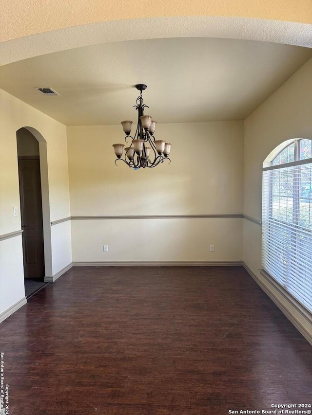 spare room featuring dark hardwood / wood-style flooring, a textured ceiling, and a notable chandelier