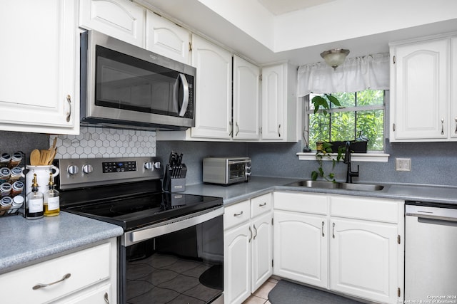 kitchen featuring white cabinets, tile patterned floors, appliances with stainless steel finishes, sink, and decorative backsplash