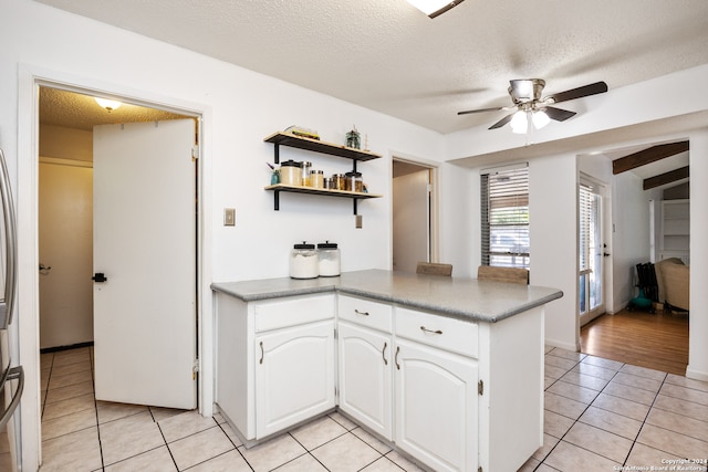 kitchen featuring a textured ceiling, ceiling fan, white cabinetry, and light tile patterned flooring