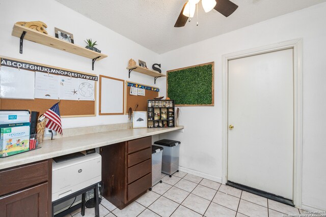 tiled office space with a textured ceiling, built in desk, and ceiling fan