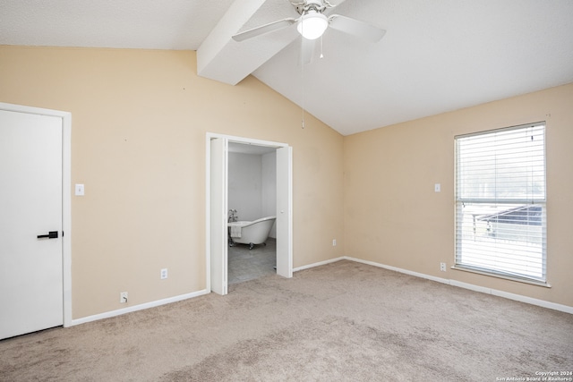 interior space with ceiling fan, ensuite bathroom, light carpet, and vaulted ceiling