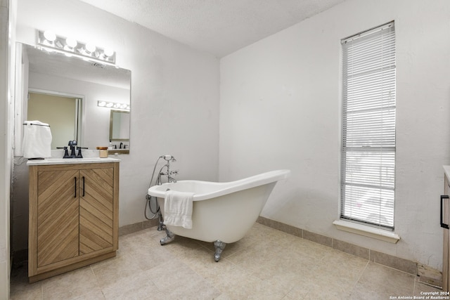 bathroom featuring a textured ceiling, vanity, and a bath