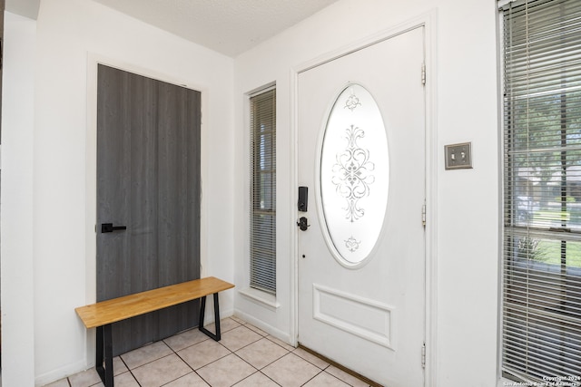 foyer entrance with a textured ceiling and light tile patterned flooring