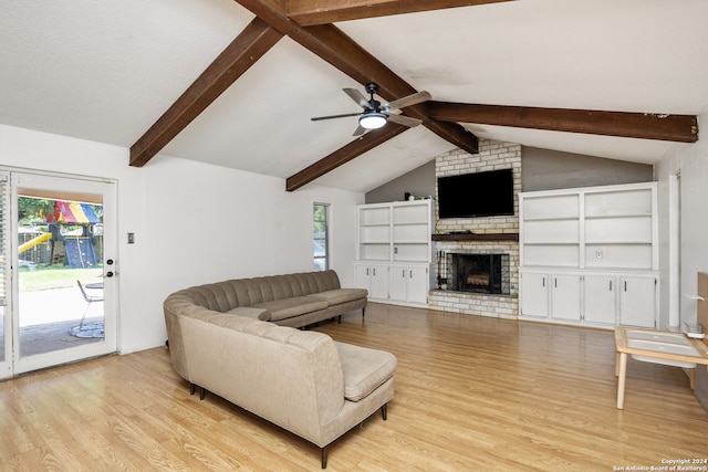 living room with a healthy amount of sunlight, ceiling fan, vaulted ceiling with beams, and a brick fireplace