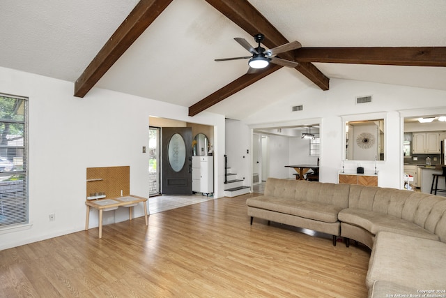 living room with ceiling fan, a textured ceiling, lofted ceiling with beams, and light hardwood / wood-style flooring