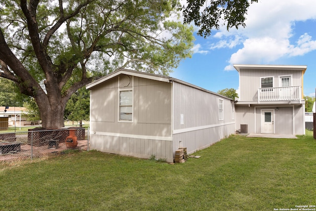 exterior space featuring a lawn, a balcony, and cooling unit