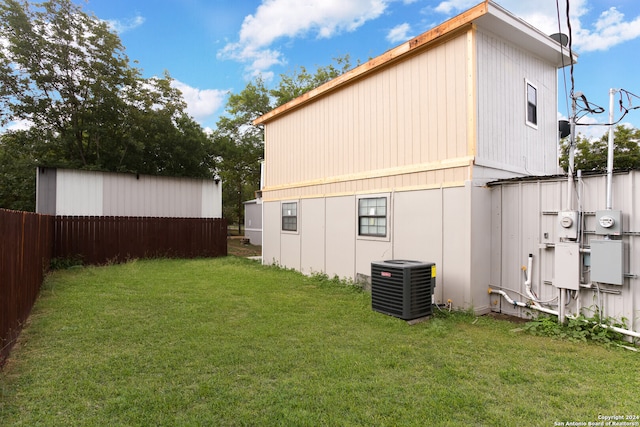 rear view of house featuring cooling unit and a lawn