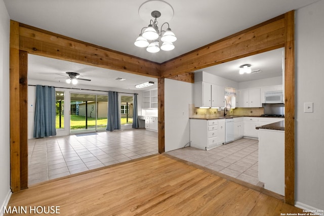 kitchen featuring ceiling fan with notable chandelier, white cabinetry, sink, and light tile patterned flooring