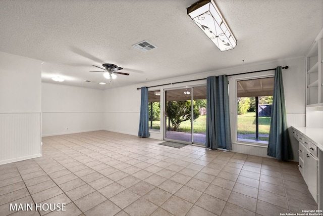 spare room with a textured ceiling, ceiling fan, and light tile patterned floors