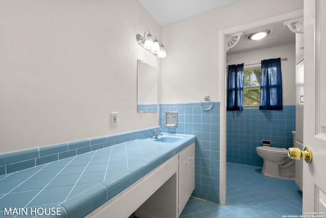 bathroom with vanity, toilet, tile walls, and tile patterned floors