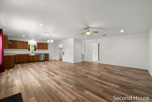 unfurnished living room with ceiling fan with notable chandelier, hardwood / wood-style floors, and sink