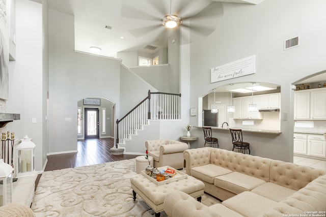 living room featuring light hardwood / wood-style flooring, high vaulted ceiling, and ceiling fan