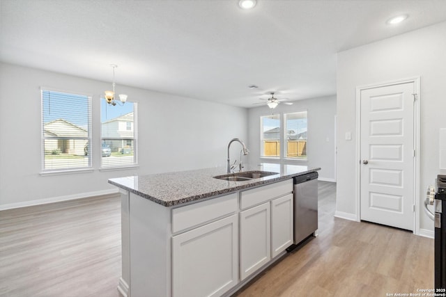 kitchen with stainless steel dishwasher, light stone counters, light wood finished floors, and a sink