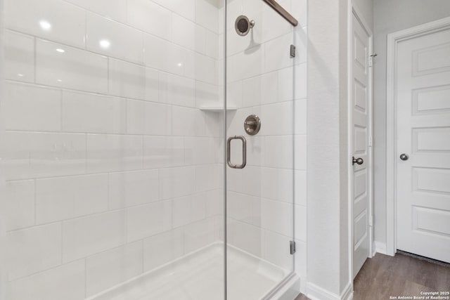 bathroom featuring wood finished floors and a shower stall