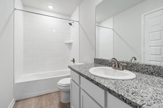 bathroom with toilet, vanity, wood finished floors, and shower / bathtub combination