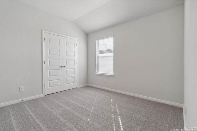 unfurnished bedroom featuring carpet, lofted ceiling, and baseboards