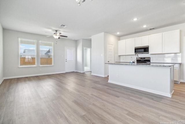 kitchen featuring stainless steel appliances, visible vents, white cabinetry, light wood-type flooring, and baseboards