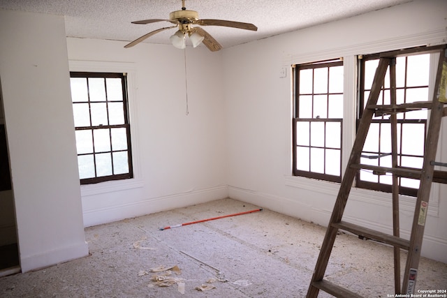 empty room with a textured ceiling and ceiling fan