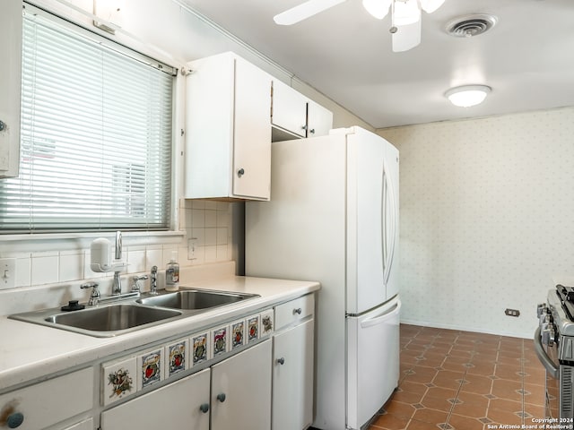 kitchen featuring white fridge, tasteful backsplash, ceiling fan, gas range, and white cabinets