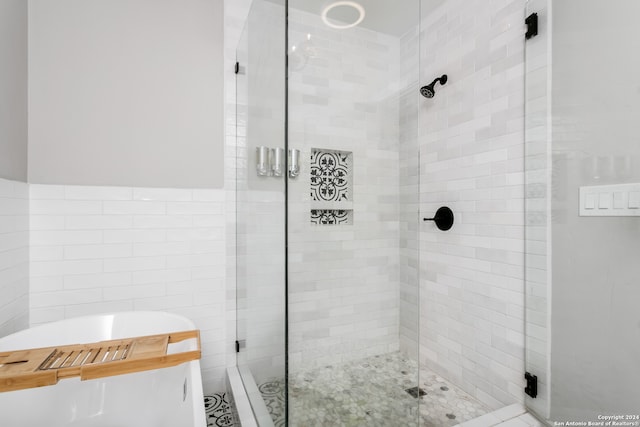 bathroom with tile walls and shower with separate bathtub