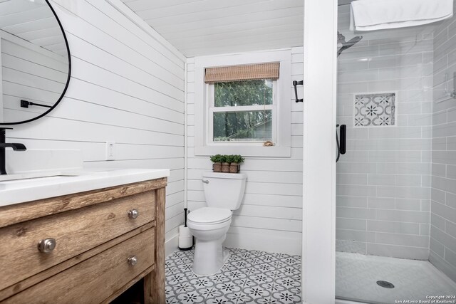 bathroom with vanity, toilet, wooden walls, and a shower with door