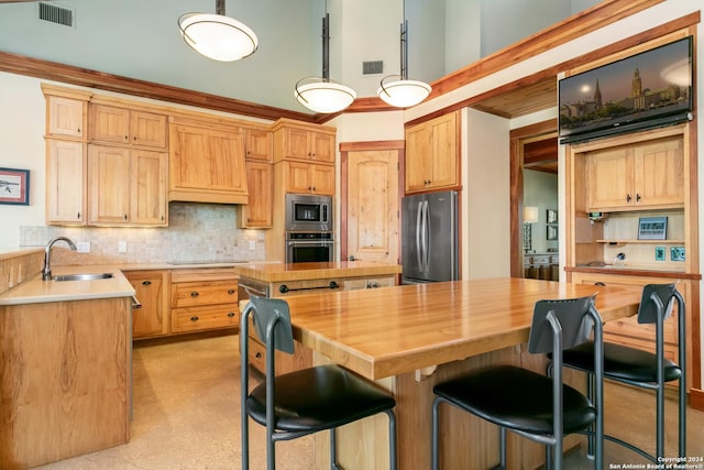 kitchen featuring visible vents, a sink, appliances with stainless steel finishes, backsplash, and a center island