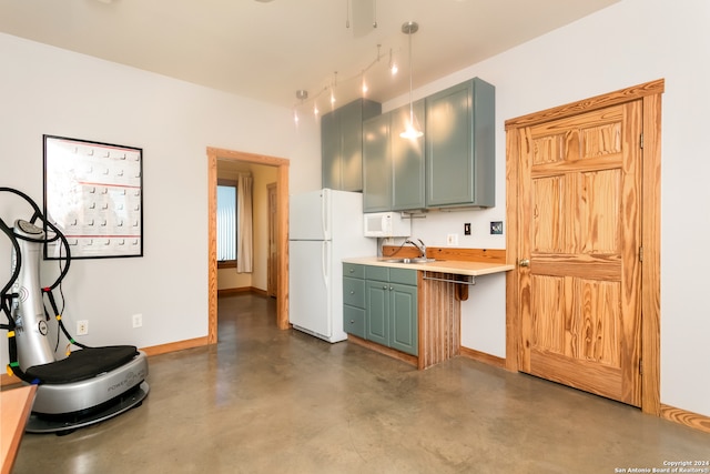 kitchen with green cabinets, white fridge, and sink