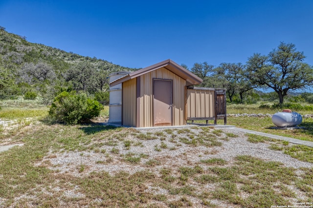 view of outdoor structure with a mountain view and a lawn