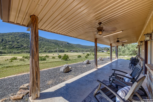 view of patio with a mountain view, a rural view, and ceiling fan