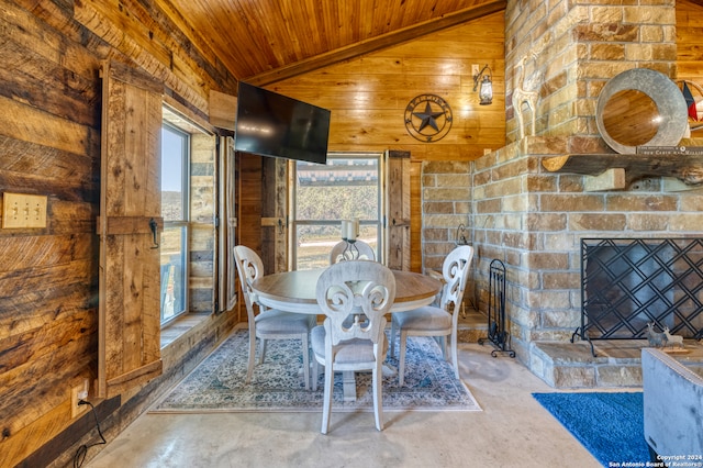 unfurnished dining area with lofted ceiling, wood ceiling, concrete floors, and a stone fireplace