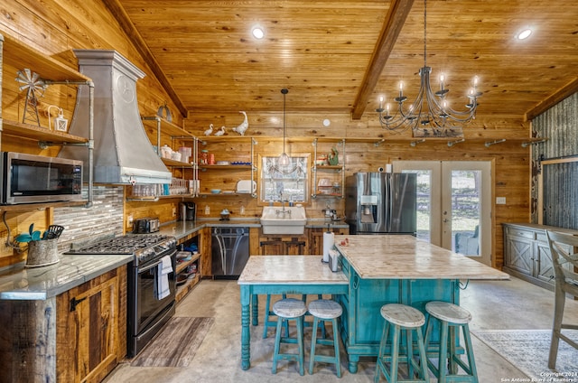 kitchen featuring a notable chandelier, custom exhaust hood, wood walls, stainless steel appliances, and a kitchen island