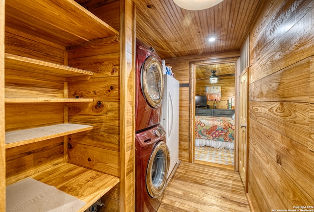 laundry area featuring stacked washer and clothes dryer, wood walls, light wood-type flooring, and wooden ceiling