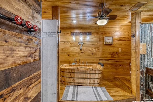 bathroom featuring wood-type flooring, ceiling fan, and wooden walls