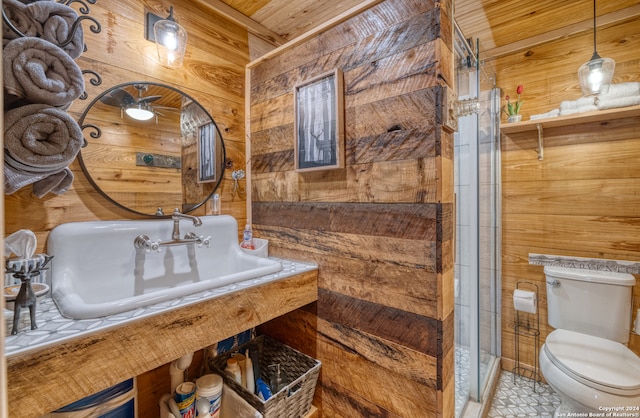 bathroom with toilet, a shower with shower door, wood walls, and tile patterned flooring