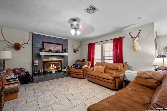 tiled living room featuring a textured ceiling, a brick fireplace, and ceiling fan