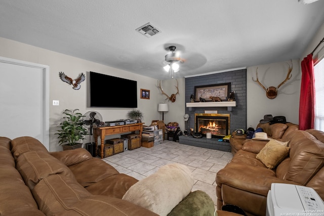 tiled living room with a textured ceiling, ceiling fan, and a fireplace