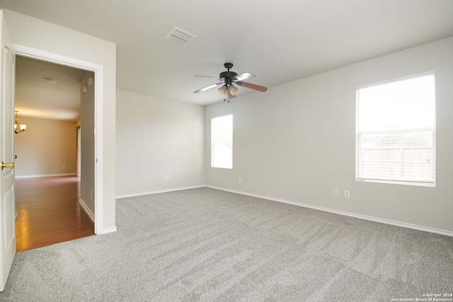 spare room with ceiling fan with notable chandelier and light hardwood / wood-style flooring