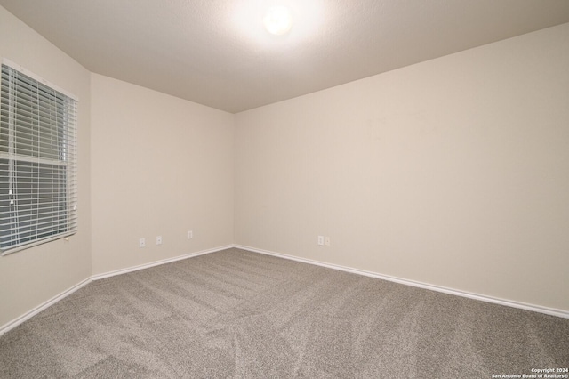 carpeted spare room featuring baseboards
