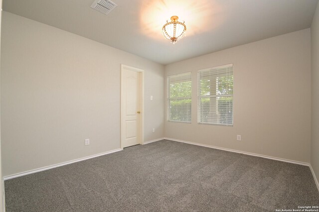 unfurnished room with baseboards, visible vents, and dark carpet