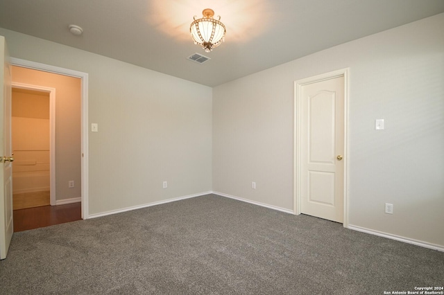 unfurnished room featuring baseboards, visible vents, and dark carpet