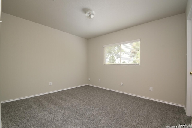 empty room with baseboards and dark colored carpet