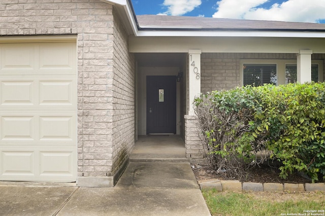 entrance to property featuring brick siding and an attached garage