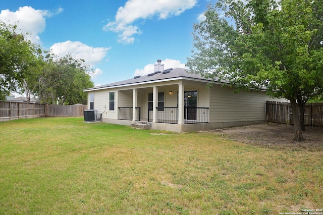 rear view of house featuring a lawn, a chimney, central AC unit, and a fenced backyard