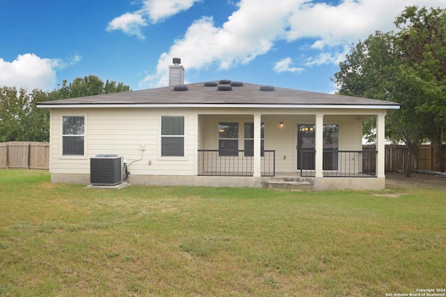 rear view of property with central AC unit, a chimney, fence, and a yard